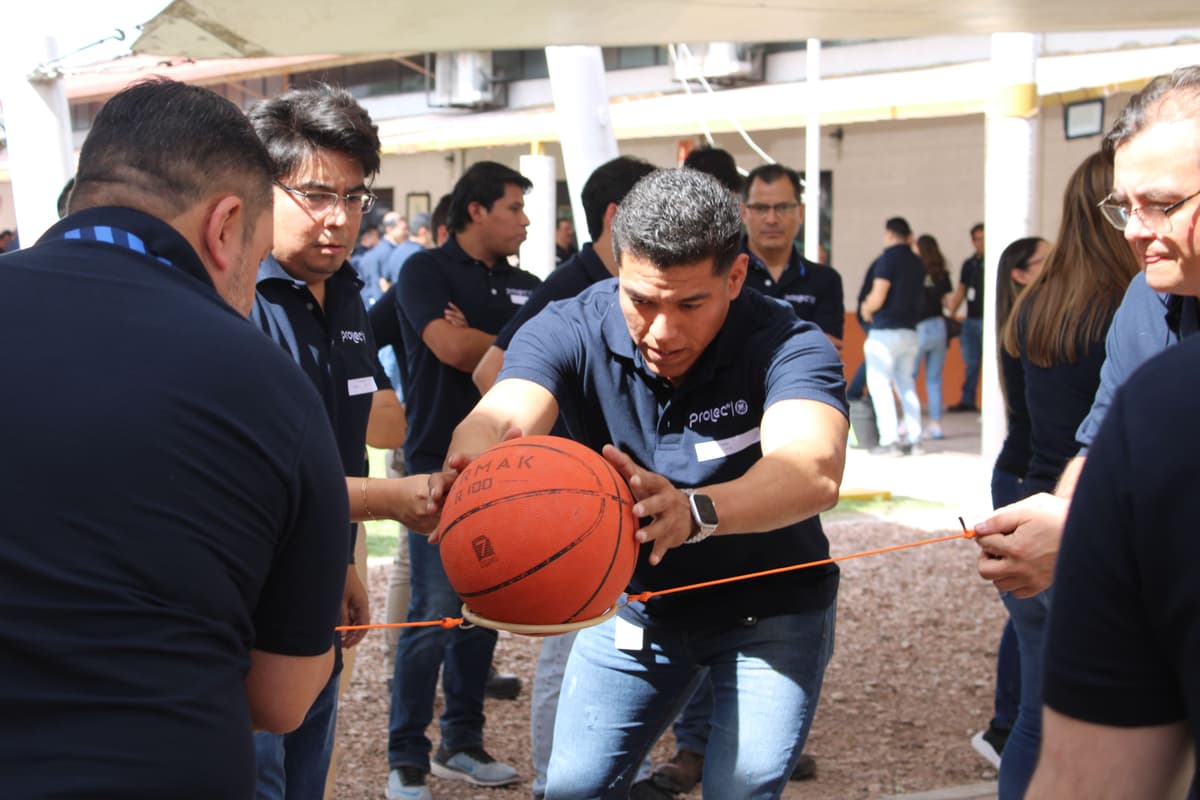 Colaboradores resolviendo un reto grupal con un balón, demostrando habilidades de coordinación y estrategia