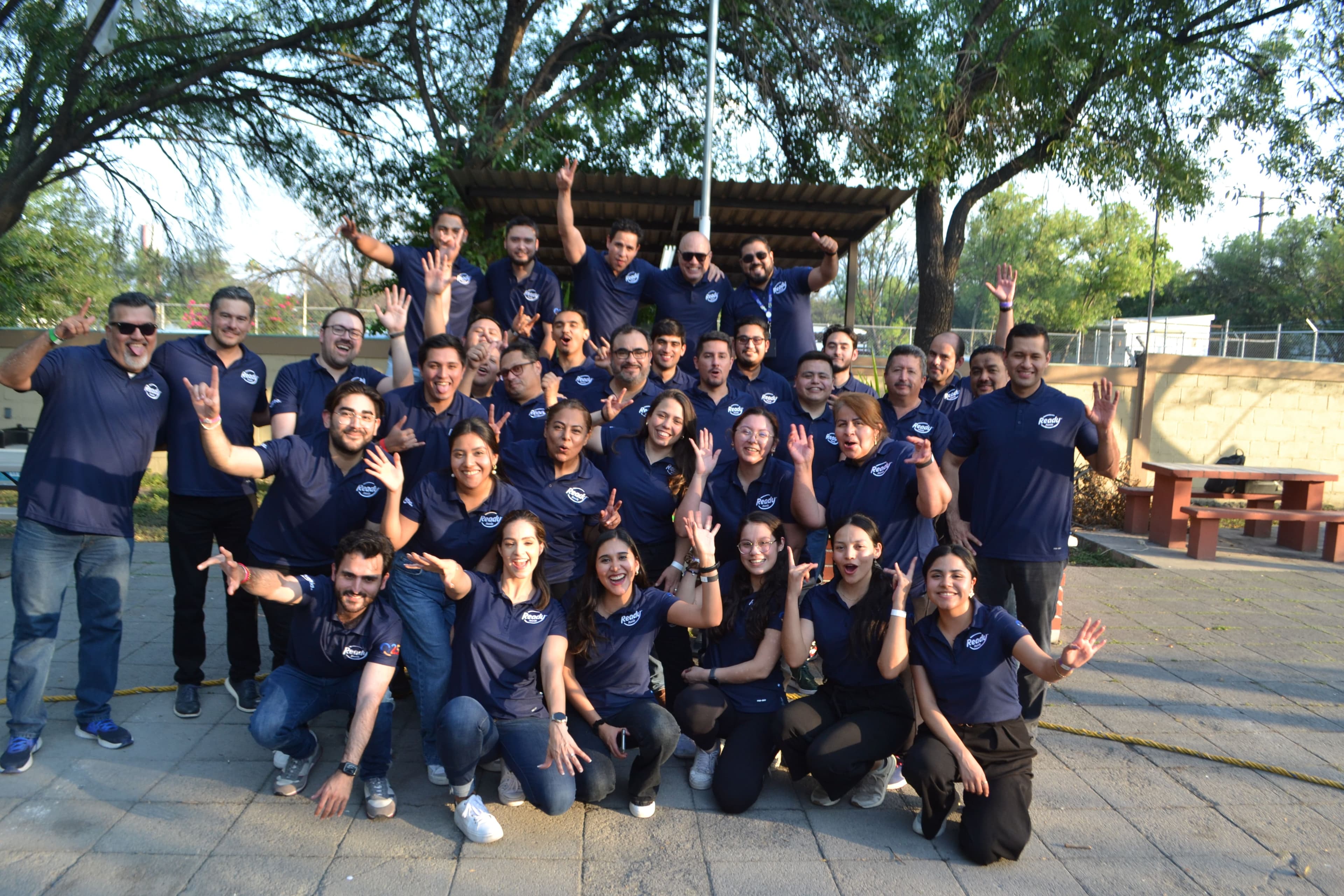 Equipo posando para una foto grupal al aire libre, mostrando la unión y la cohesión logradas en las actividades de Team Building