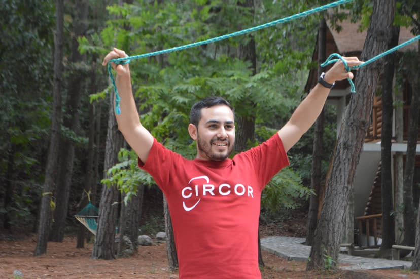 Hombre con camiseta roja levantando los brazos en señal de logro, celebrando el éxito de una dinámica grupal
